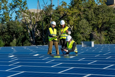 Team of diverse engineers in safety hardhats and vests are collaborating and inspecting the