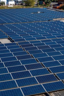 Solar panels are covering an industrial building rooftop, absorbing sunlight and converting it into