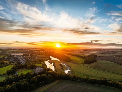 Sunset over Norham Castle and River Tweed from a drone, Norham, Northumberland, England, United