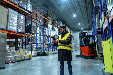 Logistics worker wearing protective clothing, scanning products with a handheld scanner in a modern