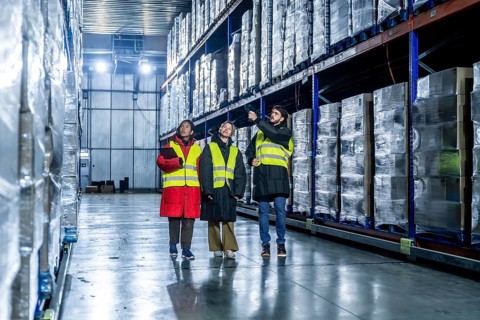 Logistics professionals, wearing warm clothing and high visibility vests, inspecting and managing