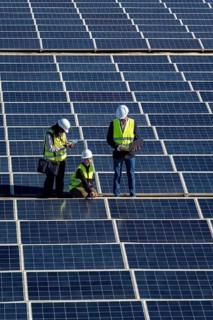 Engineers are inspecting a large solar panel array, focusing on performance and maintenance while