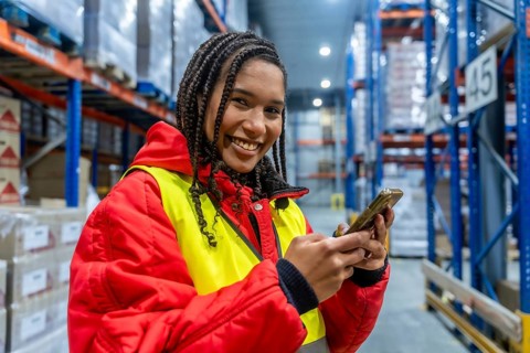 Smiling female worker managing cold storage inventory, checking orders and ensuring efficient