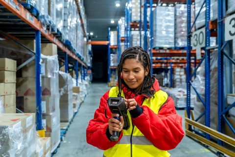 Woman worker managing inventory and scanning products with a handheld scanner in a cold storage