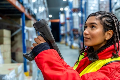 Woman worker performing stocktaking, scanning products in a refrigerated warehouse, maintaining