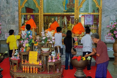 Buddhist believers Buddhists pray making offerings to statues of Buddhist monks covered with gold