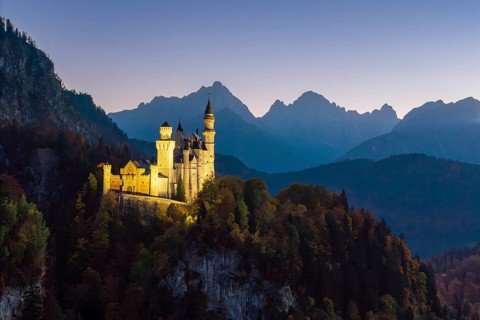 Romantic Neuschwanstein Castle at dusk in front of Bergen, Schwangau near Füssen, Ostallgäu,