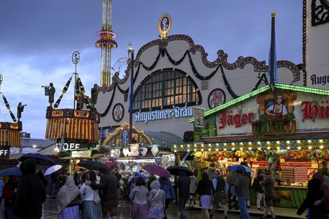 Oktoberfest visitors with umbrellas, rainy meadows, Augustiner festival tent, Munich, Bavaria,
