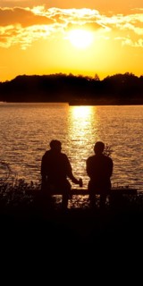 Two men sitting on a bench at sunset at Lake Gudelack, Lindow (Mark), Stechlin-Ruppiner Land nature