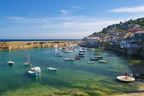 Small harbour with numerous boats and houses along the wharf, Mousehole, Cornwall, Great Britain