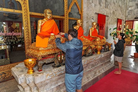 Buddhist believers Buddhists pray making offerings to statues of Buddhist monks covered with gold