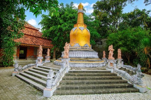 Large golden golden stupa on pedestal with steps, in front of guardian figures Buddhist monastery