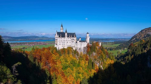 Neuschwanstein Castle overlooks a vast autumn landscape under clear skies, Schwangau, Königswinkel,