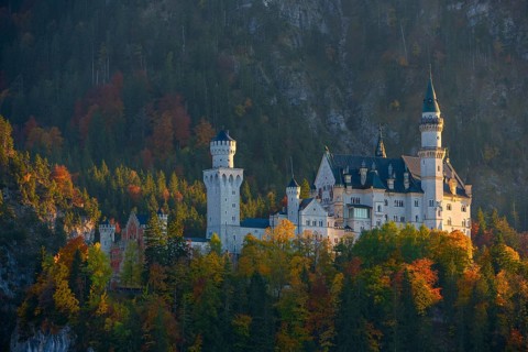 The magnificent Neuschwanstein Castle nestled in a colorful autumn forest against a mountain
