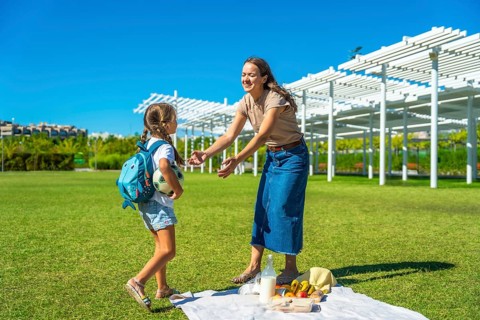 Mother and daughter enjoying a happy summer picnic in a park, parents spending quality time with