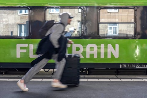 Flixtrain train on track 2 in Essen main station, passenger runs with luggage to reach his train,