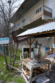 Metal oven with tea kettles in a courtyard with buildings and stacks of wood, traditional samovar,