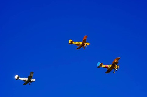 Three biplanes, a Boeing PT-17 Stearman, a Stampe-Vertongen SV-4B and a Bücker Bue 131 Jungmann fly