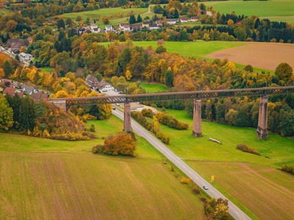 Railway bridge over an autumnal valley with colorful trees and a small village, Dornstetten,
