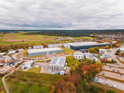 Industrial buildings surrounded by fields and trees in autumn colors under cloudy sky, Dornstetten,