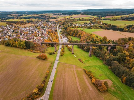Country road crosses under a bridge in an autumn landscape with fields and villages, Dornstetten,