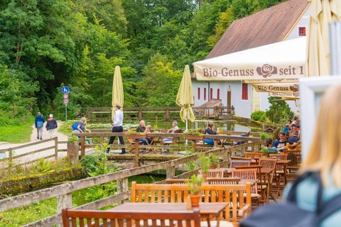 People relax in a café with a view of walkers in the countryside, Wimsener Höhle, Hayingen, Germany