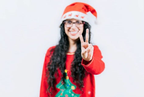 Happy girl in Christmas hat counting number TWO, isolated. Smiling girl in Christmas sweater