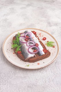 Sandwiches, Herring fish, on dark rye bread, sprinkled with onion, chili pepper and herbs, on a