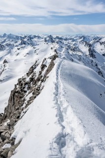 Narrow mountain ridge in winter, summit of Piz Grialetsch, view of mountain panorama with snow,