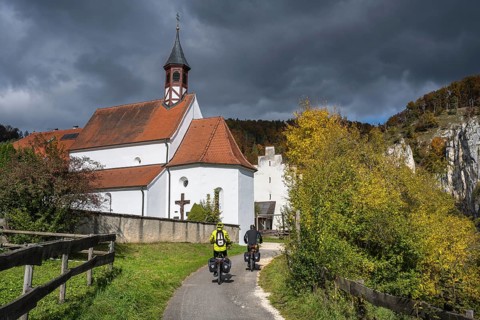 Cyclists on the Danube Valley Cycle Path in front of St. George's Basilica at Käppeler Manor near