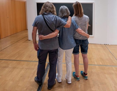 Three visitors look at a painting in an exhibition, Bavaria, Germany