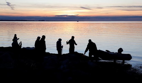 Angler on the beach during sunset, an angler docks on the shore with his inflatable boat, Fehmarn