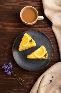 Lemon cake on brown wooden background and linen textile, cup of coffee, top view, flat lay, close