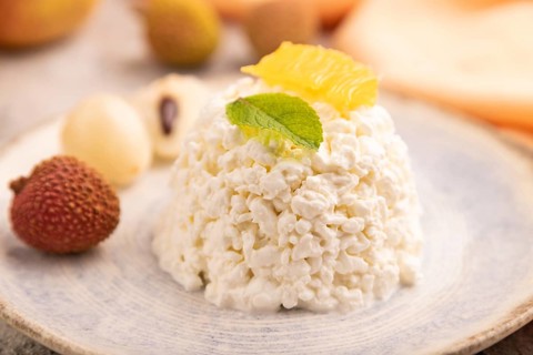 White ?ottage cheese, Curd, with orange and lychee on brown concrete background and orange textile,