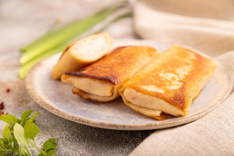 Fried crispy pancakes with meat and cheese on brown concrete background and linen textile. side
