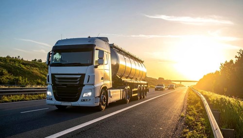 Petrol cargo truck lorry tanker driving on highway hauling oil products at sunrise, wide hilly