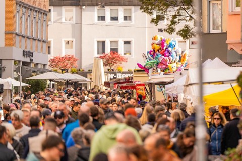 Busy shopping street in autumn, people strolling between modern buildings and colorful shops,