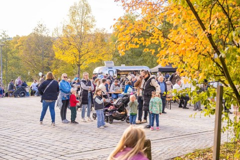 Families and children enjoy an outdoor picnic under colorful trees on an autumn day, Urschelherbst