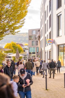 A busy street scene in a city, people walking near shops and buildings, Urschelherbst street