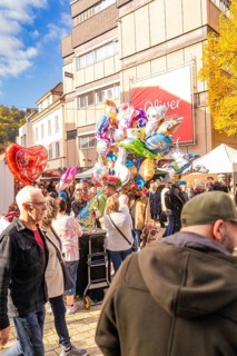 Colourful balloons over a large crowd of people on an autumn road at a happy occasion,