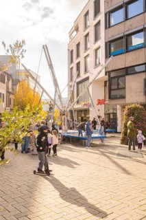 A group of people gather around bungee trampolines in an urban area, Urschelherbst Street Festival,
