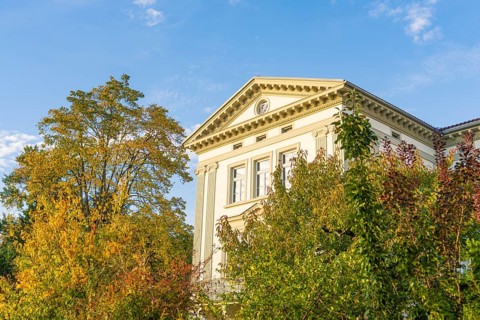 Elegant historic building surrounded by autumn trees under blue sky, Überlingen, Lake Constance,