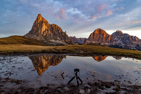 Reflection of the Ra Gusela and Tofane mountains at sunrise, in front a tripod with camera in the