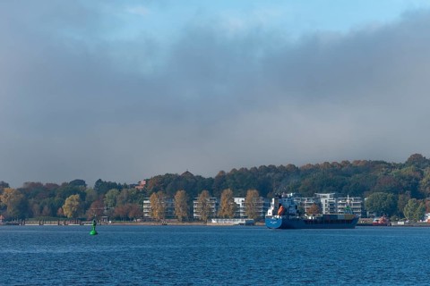 Kiel Fjord, Holtenau district, Kiel, modern apartments on the river bank, cargo ship, hillside,