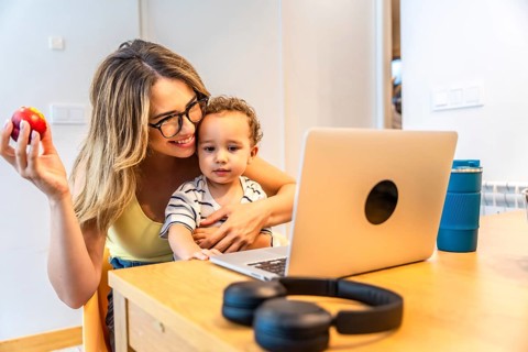 Mother holding an apple while hugging her son, both enjoying a moment together, watching something
