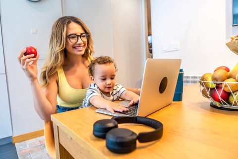 Happy mother working from home, eating healthy and taking care of her baby, while her son is