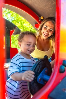 Mother and toddler having fun playing on a playground train ride, enjoying quality time together on