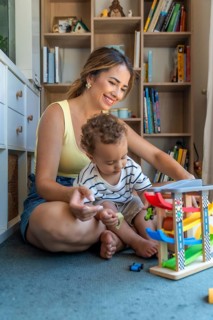 Happy mother and son playing with toy cars and garage, sitting on the floor in the playroom, having