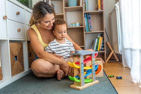 Mother and son enjoying playtime together, exploring a toy car garage in their cozy living room