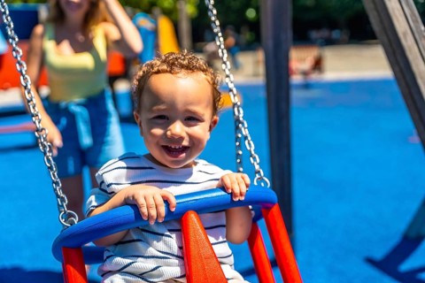 Happy toddler smiles while enjoying a swing ride at the playground, creating a joyful childhood